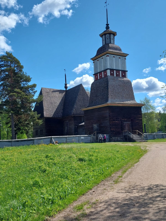 Petäjäveden vanha kirkko, vihreä ruoho, sininen taivas ja valkoiset pilvet