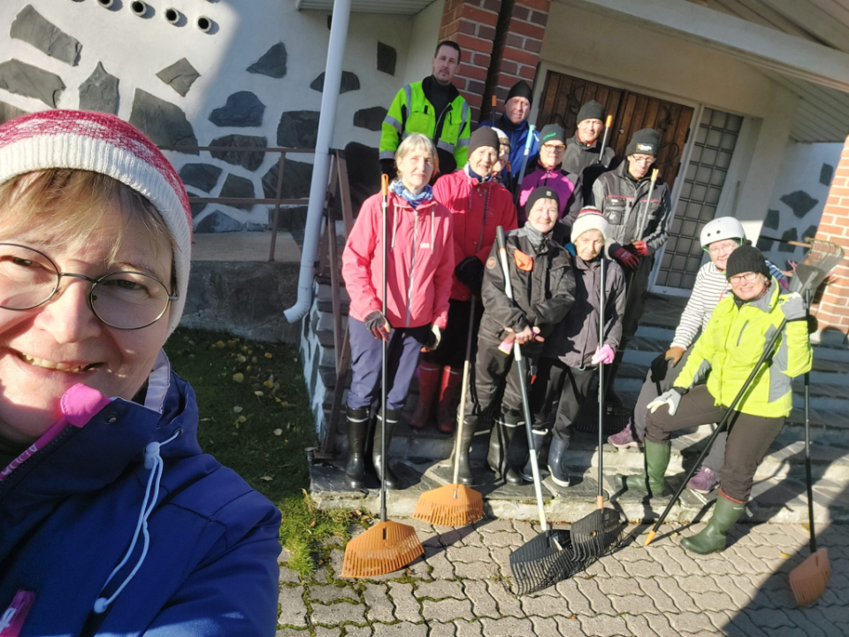 Talkoolaisia haravoineen aurinkoisilla kirkon rappusilla