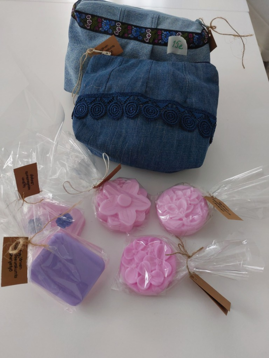 Kaksi kauniista farkkukankaasta tehtyä meikkipussi ja vaaleanpunaisia kukan muotoisia saippuoita.